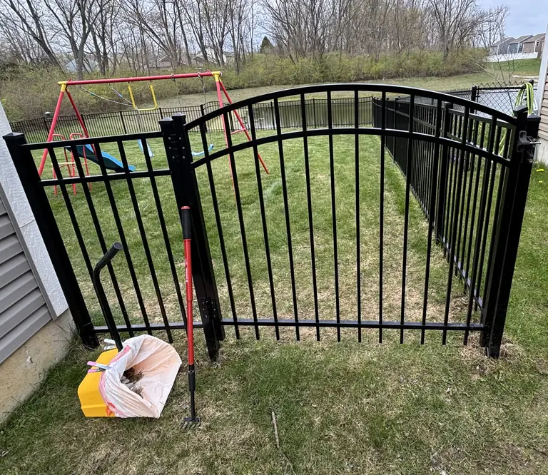 Real visit photo: a closed arched metal gate with the scooping bin and rake.