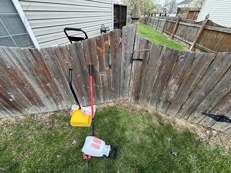 Real visit photo: the scooping bin, rake and sanitizing sprayer inside a fenced yard.