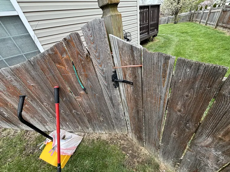 Real visit photo: a closed wooden gate with its latch fastened and cleanup tools beside it.